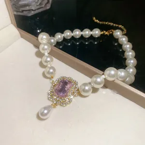 Elegante Perlenkette mit rosa Edelstein-Anhänger und goldfarbenen Details in Nahaufnahme.