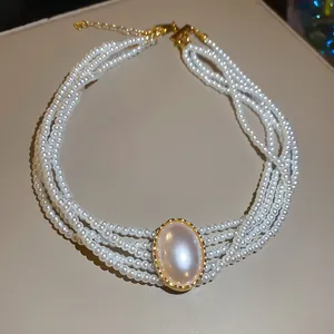 Detailansicht einer eleganten mehrreihigen Perlenkette mit großem goldenem Ovalanhänger.