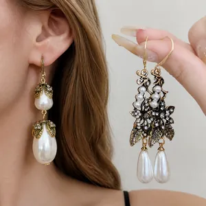Elegant vintage-style gold-tone earrings with ornate floral design and pearl drop accents.