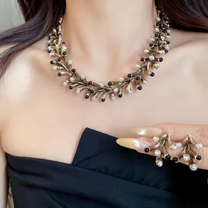 Detail view of vintage gold branch-style necklace and earring set with pearls and black beads