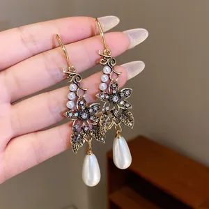 Detail view of vintage floral gold earrings with elegant teardrop pearls and crystals.