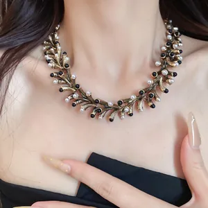 Macro view of a vintage geometric gold necklace featuring white pearl and black bead accents