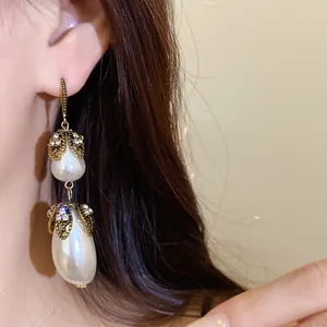 Detail view of vintage teardrop pearl earrings with ornate gold-toned crystal accents.