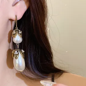 Close-up of vintage-style long earrings featuring double teardrop pearls and filigree metal