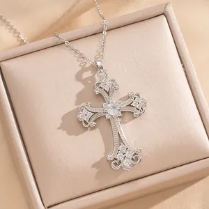 Primer plano detallado de un colgante de cruz floral calada en plata con circonitas.