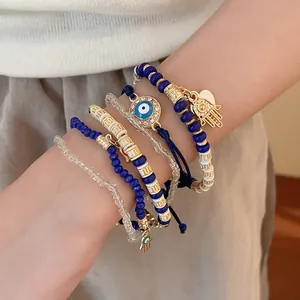 Detailed shot of layered boho bracelets featuring blue evil eye and gold hamsa charms.