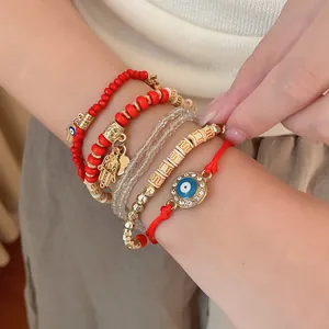 Detailed view of a red and gold beaded bracelet set with Evil Eye and Hamsa hand charms.