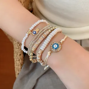 Detailed view of layered evil eye and hamsa hand beaded bracelet set on wrist