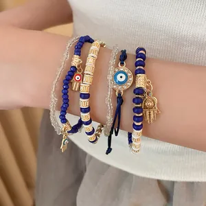 Close-up of layered bohemian Evil Eye and Hamsa hand charm beaded bracelet set