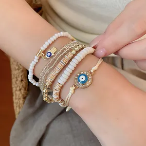 Detail of evil eye charm bracelet set with white acrylic and gold-toned beads on wrist