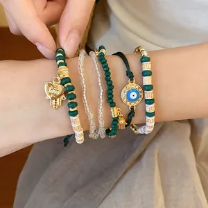 Close-up of bohemian beaded bracelet set with evil eye and heart charms on wrist.