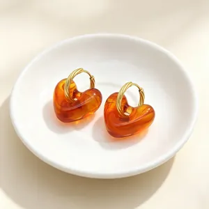 Macro-weergave van vintage hartvormige oorbellen van hars met gedraaide gouden hoops
