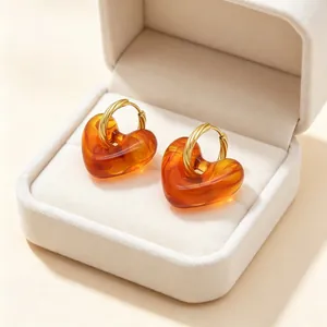 Close-up van vintage amberkleurige hartvormige oorbellen met gouden gedraaide ringen