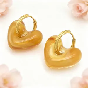 Detail van vintage hars hart oorbellen met goudkleurige getwiste stalen ringen.