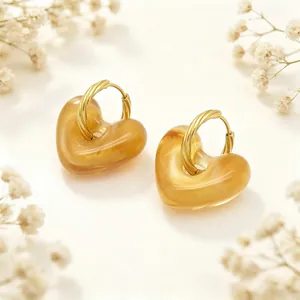 Detailopname van retro amberkleurige hartvormige oorbellen met gedraaide gouden oorringen.