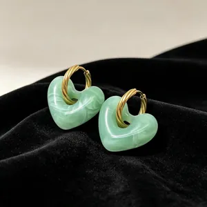 Detailweergave van vintage hartvormige oorbellen van groen marmerhars met gouden draaicirkels