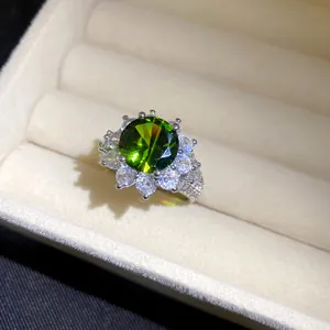 Detaillierte Nahaufnahme eines eleganten runden grünen Zirkon-Blumenrings in Silber