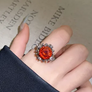 Nahaufnahme eines orangefarbenen Zirkon-Blumenrings am Finger mit feinen Kristalldetails.