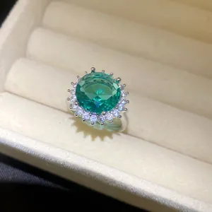 Nahaufnahme eines runden smaragdgrünen Zirkonrings mit funkelnder Blütenfassung
