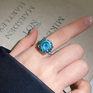 Nahaufnahme eines luxuriösen blauen Zirkonia-Blumenrings an einem Finger mit Glanz