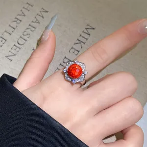 Nahaufnahme eines silbernen Rings mit einem leuchtenden orangen Zirkon-Blumendesign.