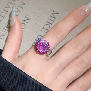 Nahaufnahme eines Silberrings mit einem funkelnden runden rosa Zirkon an der Hand