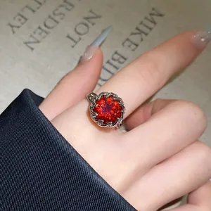 Nahaufnahme eines funkelnden runden roten Zirkon-Blumenrings getragen an einem Finger
