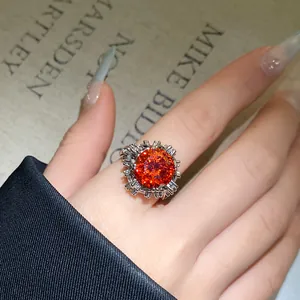 Nahaufnahme eines eleganten offenen Rings mit orangefarbenem Zirkonia-Blumenmuster.