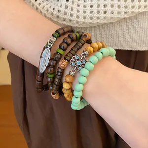 Detail view of bohemian beaded bracelet set with feather and flower charms on wrist.