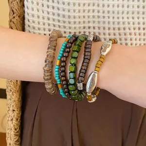Close-up detail of layered bohemian style beaded bracelets featuring turquoise and wood beads.