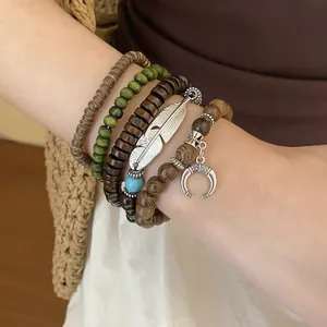 Close-up of bohemian beaded bracelets featuring silver feather and crescent moon charms