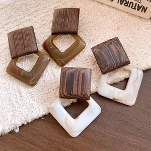 Detail of retro geometric wood and acrylic dangle earrings in Maillard style