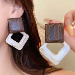 Close-up of vintage geometric wood and acrylic drop earrings in Maillard style.