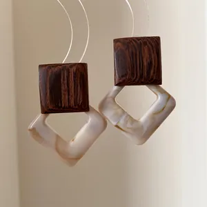 Detail of vintage geometric earrings with wood texture and marble pattern acrylic.