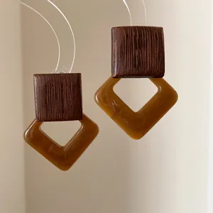 Detail view of vintage geometric earrings with dark wood and amber acrylic dangles.
