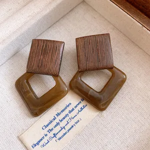 Macro detail of vintage geometric earrings crafted with wood and brown acrylic squares