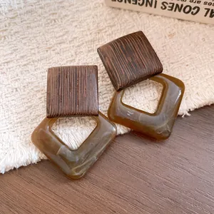 Close-up of vintage geometric earrings with wood grain and marbled acrylic texture