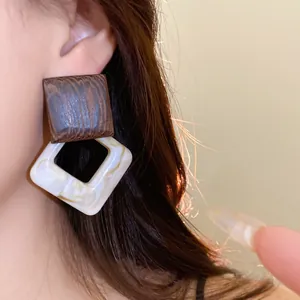 Detailed view of vintage wood and marble acrylic geometric drop earrings worn on ear