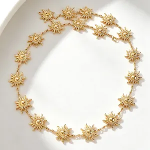 Detail einer goldenen Sonnenkette mit hohlen geometrischen Sonnenmotiven auf Weiß.