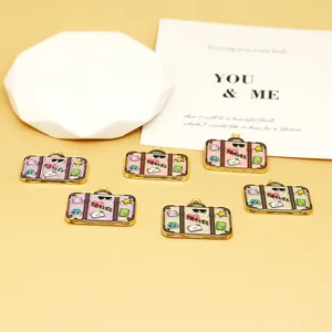 Macro view of colorful enamel travel suitcase charms with heart pattern and travel text.