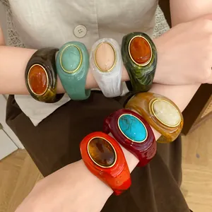 Detailaufnahme von bunten marmorierten Acryl-Armreifen mit elegantem ovalem Mittelteil.