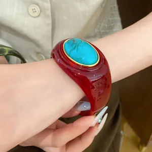 Nahaufnahme eines roten Acryl-Armreifs mit türkisähnlicher ovaler Einlage