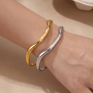 Detailed view of irregular wavy stainless steel bangles in gold and silver finish.