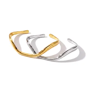 Close-up of irregular wave-shaped stainless steel cuff bracelets in gold and silver