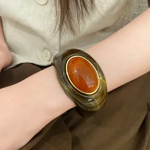 Nahaufnahme eines Retro-Acryl-Armbands mit ovalem Farbverlauf in Bernstein- und Marmorbraun.