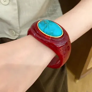 Nahaufnahme eines roten Acryl-Armreifs mit ovalem Türkisstein im Vintage-Stil für Damen.