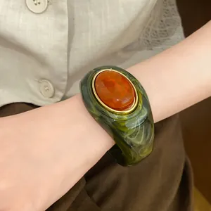 Detailansicht eines grünen Marmor-Acrylarmbands mit orangefarbenem ovalem Schmuckstein