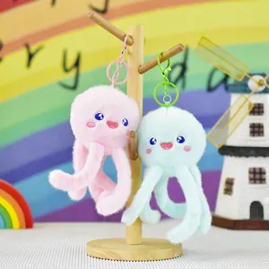 Close-up of pink and mint green plush jellyfish keychains hanging on a wooden stand
