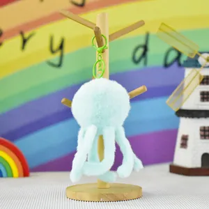 Detail view of a soft mint green plush jellyfish keychain hanging on a wooden stand