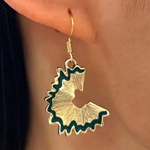 Close-up detail of creative pencil shaving drop earring with green enamel and gold finish
